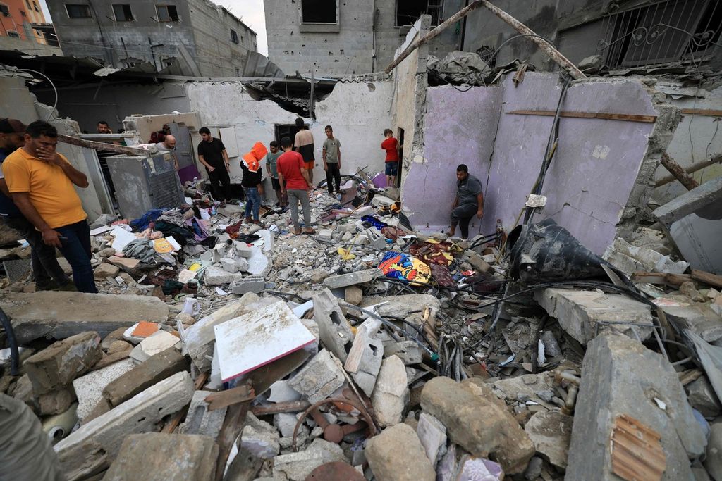Warga Palestina mengecek reruntuhan bangunan setelah serangan Israel ke Khan Yunis, Minggu (29/10/2023). 