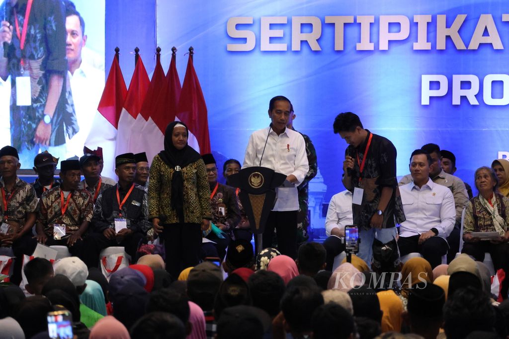 Presiden Joko Widodo membagikan sepeda kepada warga yang menjawab kuis di pembagian sertifikat tanah di Banyuwangi, Selasa (30/4/2024). Di kiri Presiden adalah Supahmi, sedangkan di kanan adalah Agus Kurniawan. 