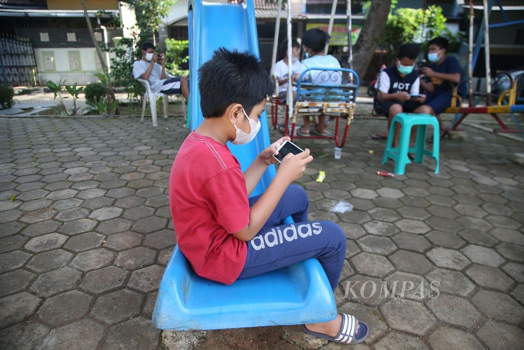 Anak-anak bermain gim daring di kawasan Pamulang, Tangerang Selatan, Banten, Sabtu (13/3/2021). Paparan gim daring semakin masif menjangkiti anak-anak seiring akses gawai yang mudah sebagai dampak pembelajaran sekolah via daring. 