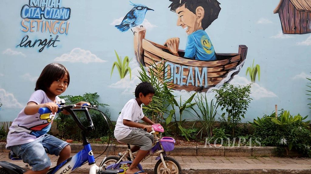Anak-anak bersepeda melintasi mural bertuliskan Raihlah Cita-citamu Setinggi Langit di kawasan Larangan Selatan, Tangerang, Banten, Senin (26/6/2017). Seni mural menjadi salah satu sarana memotivasi masyarakat untuk meraih kesuksesan di masa depan.
