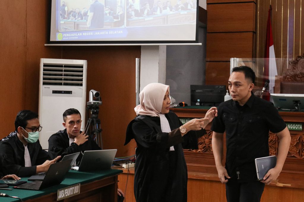 Jaksa penuntut umum berbincang dengan terdakwa Ricky Rizal sebelum sidang dimulai di Pengadilan Negeri Jakarta Selatan, Senin (2/1/2022). 