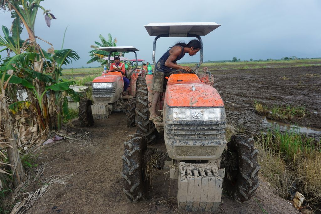 Cahyo dan Tardi, warga Desa Belanti Siam, Kabupaten Pulang Pisau menggunakan mesin traktor bantuan pemerintah di sawah mereka, Jumat (4/9/2020). Kawasan itu merupakan kawasan program lumbung pangan nasional.