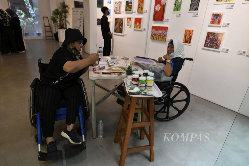 Sri Puryantini (kiri) membantu rekannya, Cica Marlisa, menyelesaikan lukisan dalam pameran bertajuk "Selayang Pandang" di Galeri Mitra Hadiprana, Kemang, Jakarta Selatan, Kamis (26/1/2023). 