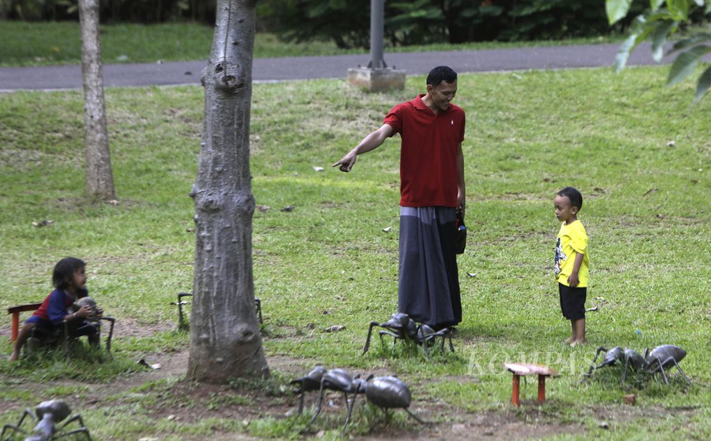 Sebuah keluarga tengah bermain di sekitar patung serangga di Tebet Eco Park, Jakarta Selatan, Kamis (21/3/2024).  