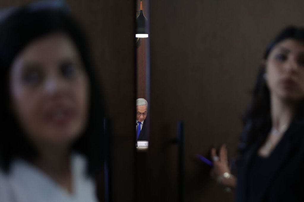 Perdana Menteri Israel Benjamin Netanyahu terlihat dari celah pintu saat ia memimpin sidang kabinet di kantornya di Jerusalem, Minggu (19/2/2023). 
