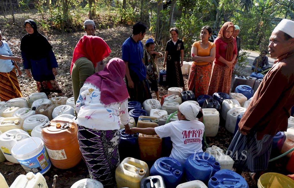 Warga antre air bersih yang diberikan Palang Merah Indonesia dengan menggunakan truk di Desa Kunjorowesi, Kecamatan Ngoro, Kabupaten Mojokerto, Jawa Timur, Senin (5/9). Keringnya mata air dan ketiadaan air hujan untuk ditampung di tandon air membuat warga di desa itu kesulitan mendapatkan air bersih sejak dua bulan lalu. Mereka membutuhkan bantuan  air dari berbagai pihak.