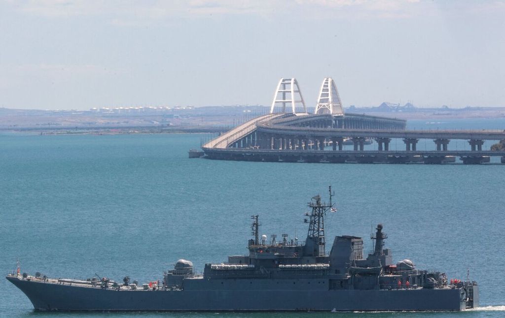 Foto yang diambil per 17 Juli 2023 ini menunjukkan kapal perang Rusia berlayar di sekitar Jembatan Krimea setelah serangan ledakan di jembatan tersebut pada Senin (17/7/2023). 
