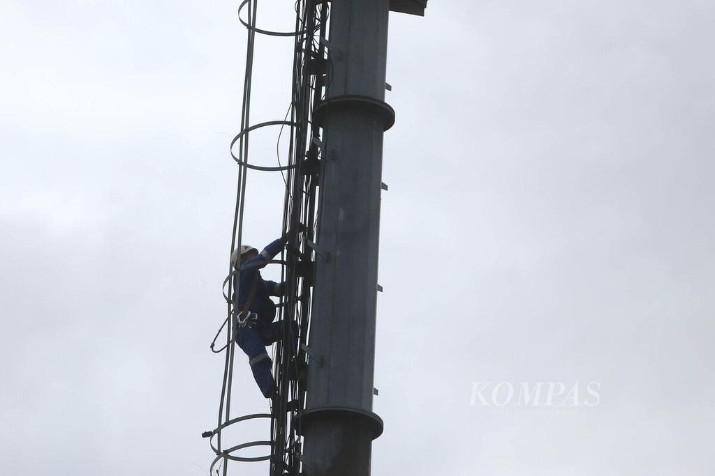 Teknisi memanjat menara untuk melakukan pengecekan dan perawatan perangkat <i>base transceiver station</i> milik XL Axiata pascabanjir di kawasan Bendungan Hilir, Jakarta Pusat, Rabu (26/2/2020).