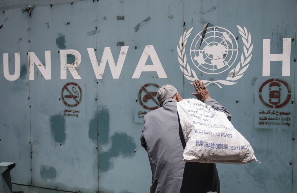 Seorang pria Palestina berdiri di depan lambang Badan PBB untuk Bantuan Pengungsi Palestina (UNRWA) di kantor lembaga itu di Gaza, 31 Juli 2018.