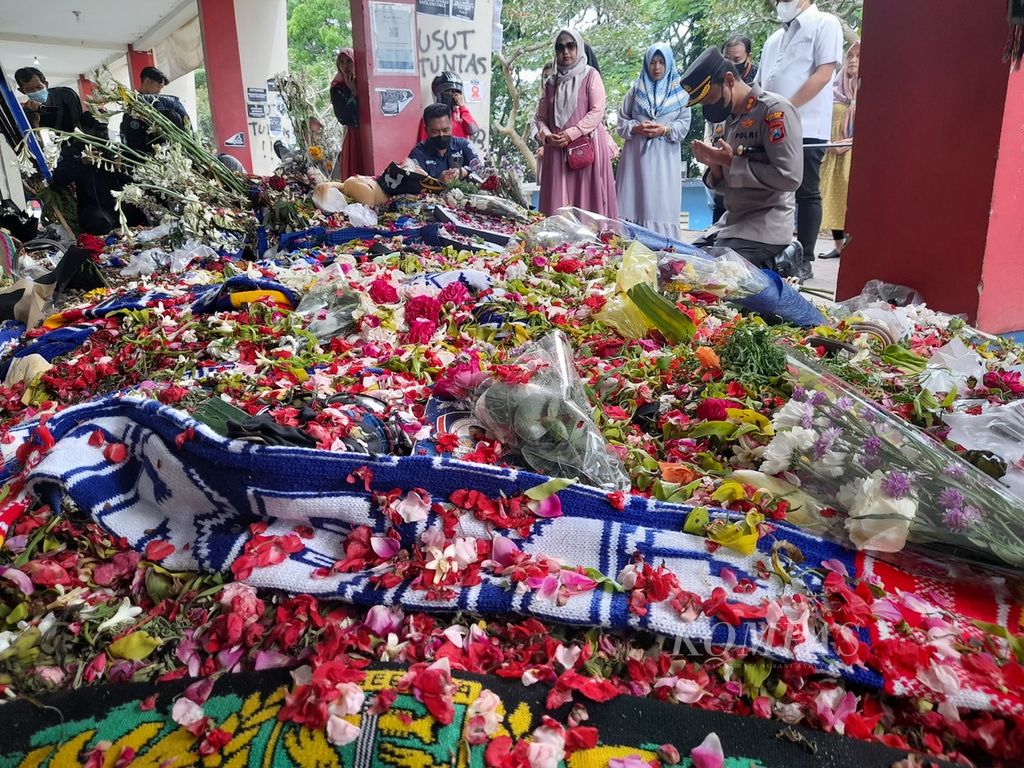 Kepala Polres Malang yang baru, Ajun Komisaris Besar Putu Kholis Aryana, Selasa (11/10/2022), berdoa di depan hamparan bunga tabur yang menumpuk di depan pintu 13 Stadion Kanjuruhan.
