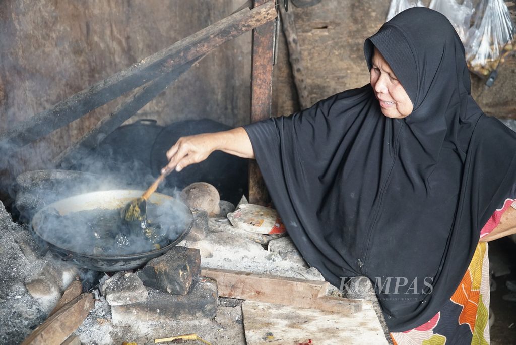 Rasuhatni (69) memasak gulai ayam galundi di rumahnya, Nagari Sulit Air, Kecamatan X Koto Diatas, Kabupaten Solok, Sumatera Barat, Kamis (26/5/2022). Gulai khas Sulit Air ini berwarna hitam karena dicampur bubuk buah galundi.