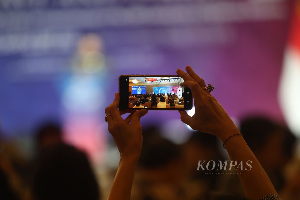 Tangan seorang peserta acara peringatan 50 tahun hubungan diplomatik Indonesia-Korea Selatan merekam jalannya acara di Ballroom Hotel Mulia Senayan, Jakarta, Kamis (30/11/2023). 