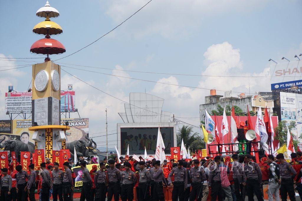 Polisi berjaga di lokasi aksi unjuk rasa ratusan buruh di Bandar Lampung, Selasa (1/5/2018). Sekitar 300 buruh yang tergabung dalam Federasi Serikat Buruh Karya Utama (FSBKU) menggelar unjuk rasa memperingati Hari Buruh Internasional yang diperingati pada 1 Mei.