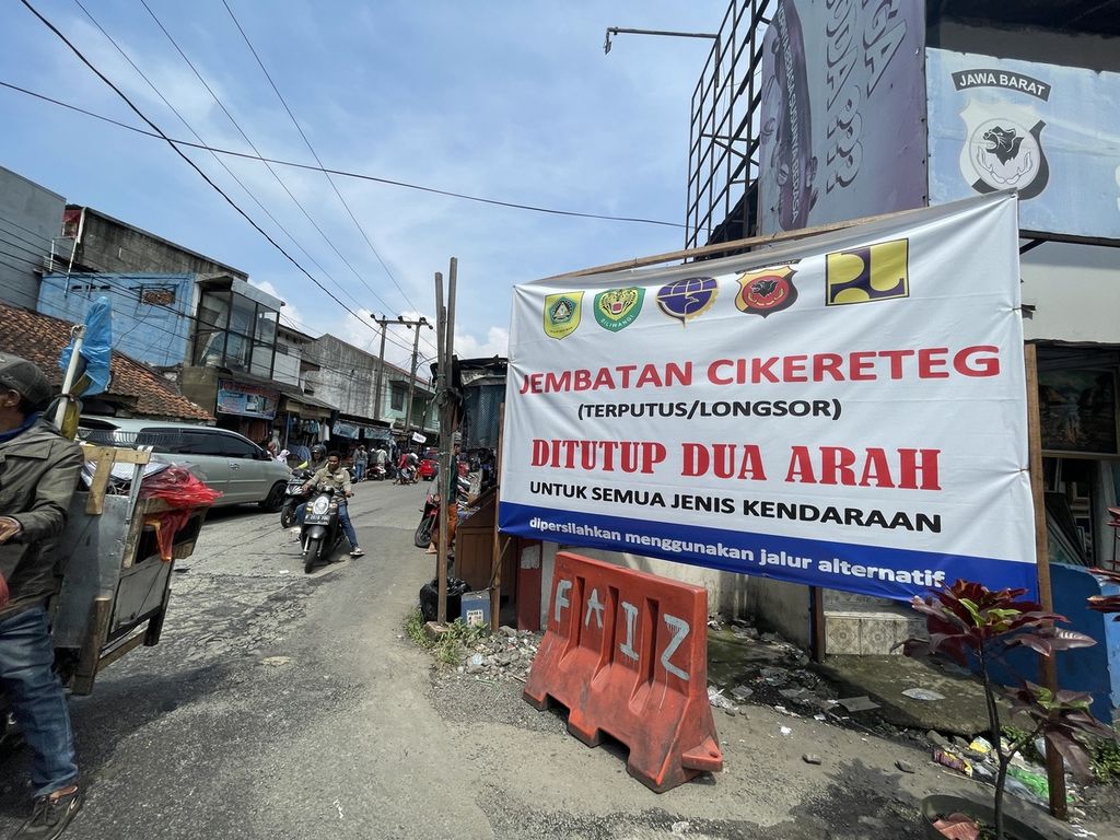 Spanduk berisi informasi penutupan total Jembatan Cikereteg terpasang di jalan samping Pasar Cikereteg, Kabupaten Bogor, Jawa Barat, yang dijadikan jalur alternatif, Minggu (12/3/2023).