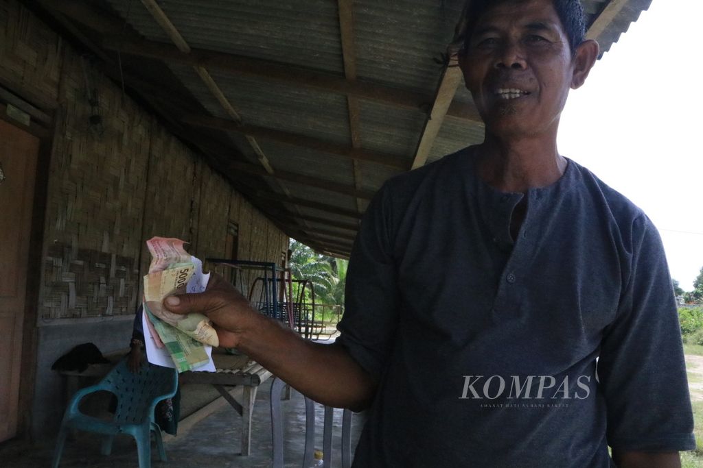 Turino (57), nelayan, menunjukkan uang hasil penjualan kepiting bakau dari hutan mangrove di Desa Tanjung Rejo, Kecamatan Percut Sei Tuan, Kabupaten Deli Serdang, Sumatera Utara, Selasa (22/11/2022). 