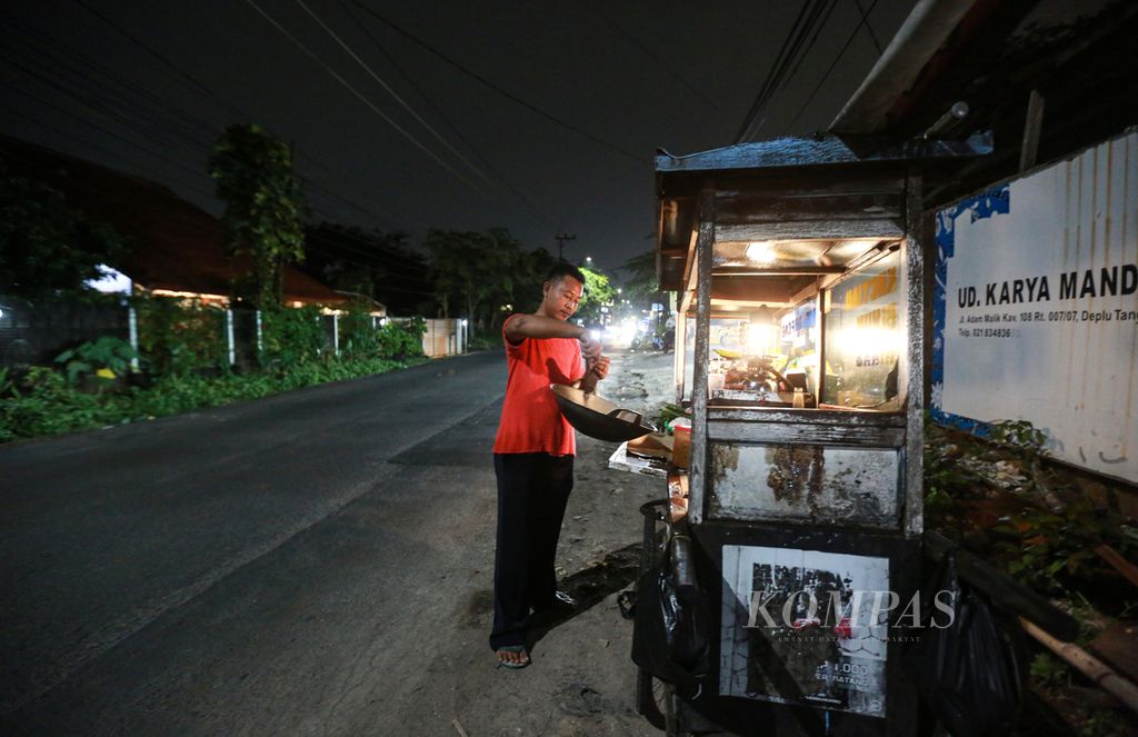 Taufik, pedagang nasi goreng keliling saat mempersiapkan nasi goreng pesanan pelanggan di pinggir jalan H Adam Malik, Kota Tangerang, Banten, Rabu (12/10/2022) malam. Pria kelahiran Tegal, Jawa Tengah ini mengakui telah 25 tahun berjualan nasi goreng keliling. Serial Urban Koming