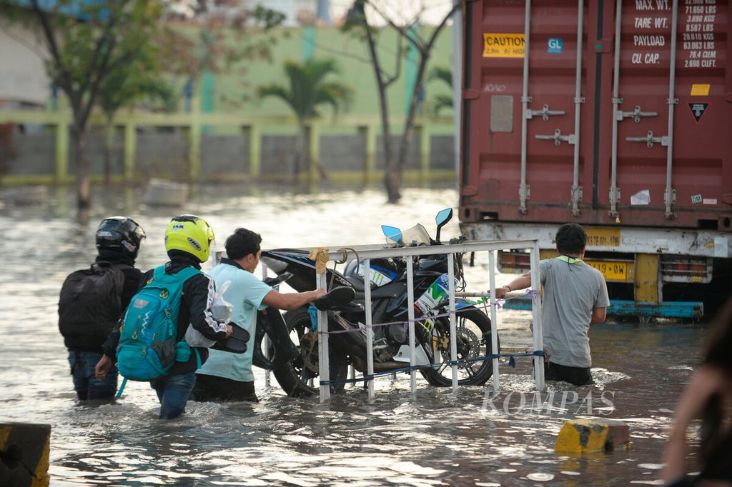 Warga memanfaatkan jasa angkut untuk membawa kendaraannya agar tidak terendam banjir rob di Pelabuhan Tanjung Emas, Kota Semarang, Jawa Tengah, Senin (20/6/2022). 
