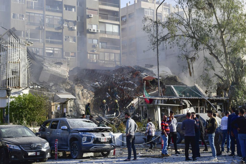 Warga berkumpul di dekat gedung konsuler Kedutaan Besar Iran di Damaskus, Suriah, yang hancur akibat serangan udara pada 1 April 2024. Iran menuding serangan itu dilancarkan Israel.