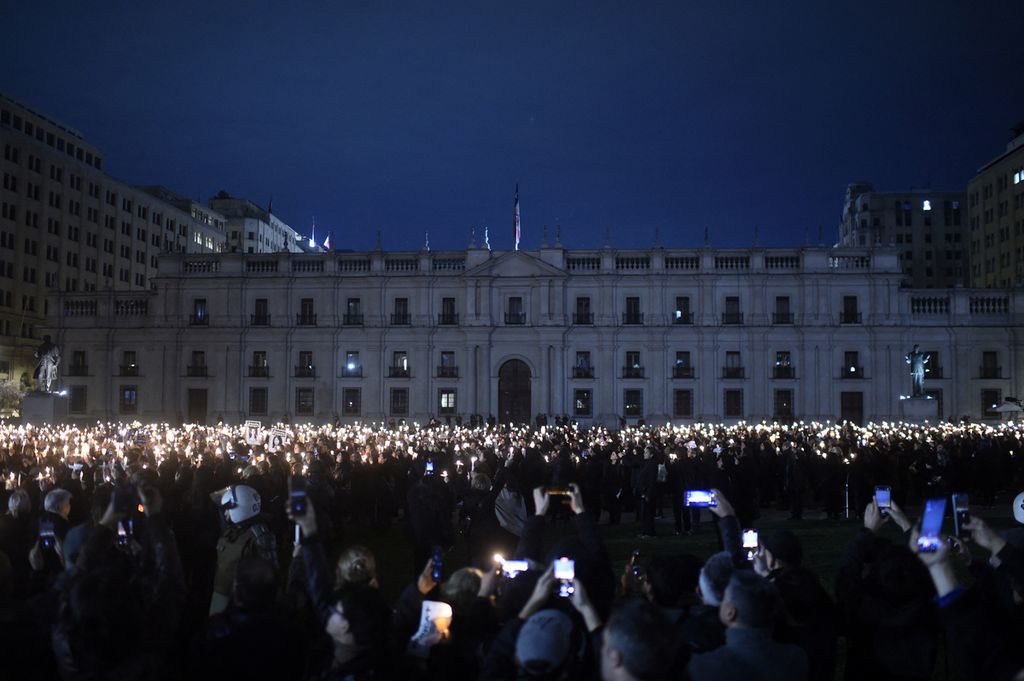 Nyala lilin dan ponsel oleh massa di depan Istana Kepresidenan La Moneda di Santiago, Chile, 2023. Demonstrasi itu untuk memperingati 50 tahun kudeta militer yang dipimpin oleh Jenderal Augusto Pinochet melawan sosialis Presiden Salvador Allende.