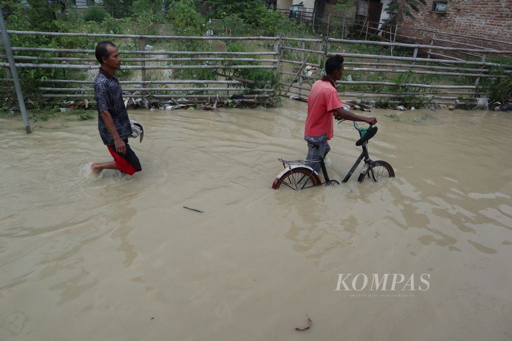 Warga melewati banjir luapan Sungai Ciberes di Desa Gunungsari, Kecamatan Waled, Kabupaten Cirebon, Jawa Barat, Sabtu (22/1/2022) siang. Sekitar 850 rumah warga terendam. Selain karena hujan deras, banjir juga dipicu penyempitan sungai.