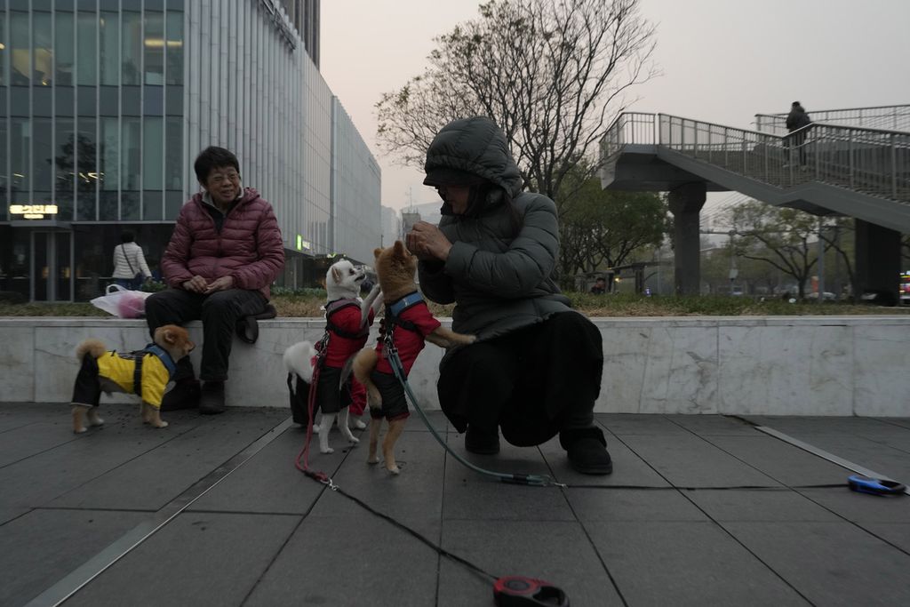 Warga bermain dengan anjing-anjingnya di luar sebuah mal di Beijing, China, 21 November 2023. 