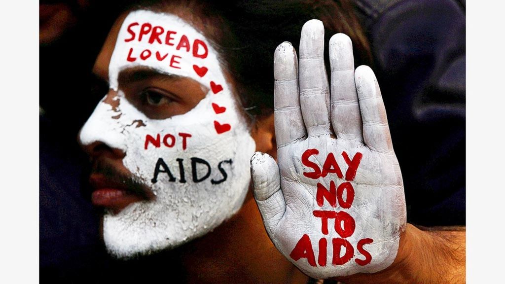 Seorang laki-laki menunjukkan wajah dan tangan yang dicat putih yang bertuliskan pesan-pesan dalam kampanye kesadaran HIV/AIDS pada peringatan Hari AIDS Sedunia di Chandigarh, India, 1 Desember 2017.