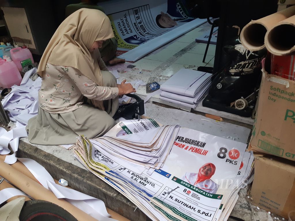 Tampak salah satu pekerja PT Quantum Graph memasang ring besi pada setiap spanduk untuk kampanye seorang calon anggota legislatif di daerah Pagarsih, Kota Bandung, Jawa Barat, 11 Desember 2023. Tempat ini telah memproduksi 5.000 spanduk dalam sepekan terakhir.