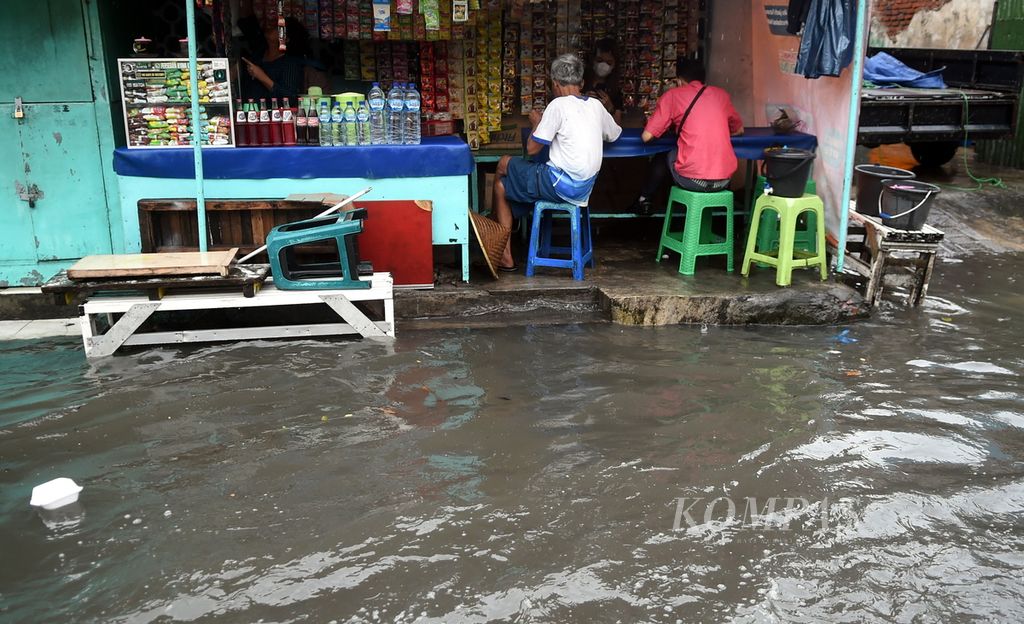 Warga di warung kopi saat banjir di Jalan Jagir Wonokromo Wetan, Surabaya, Jawa Timur, Selasa (11/1/2022). 