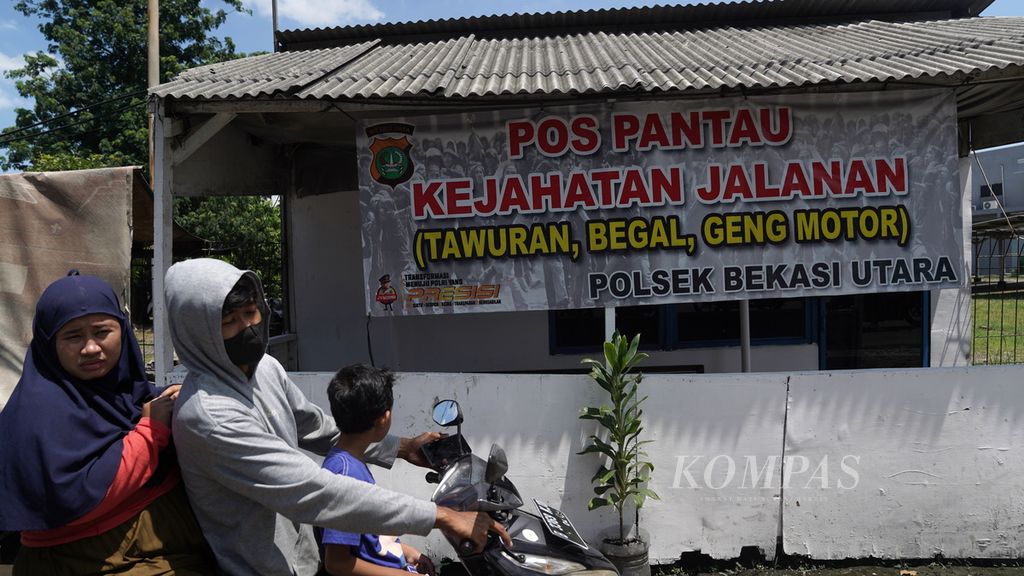 Warga melintasi pos posko kejahatan jalanan di Teluk Pucung, Bekasi Utara, Jawa Barat, Selasa (29/11/2022). 
