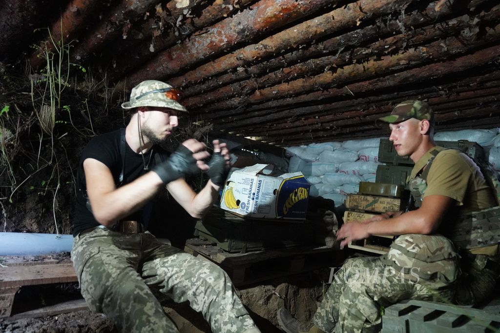 Two Ukrainian soldiers sit in a trench at a location around the front line of fighting in eastern Ukraine, Friday, July 8, 2022. The soldiers used the trenches to protect themselves from artillery attacks.