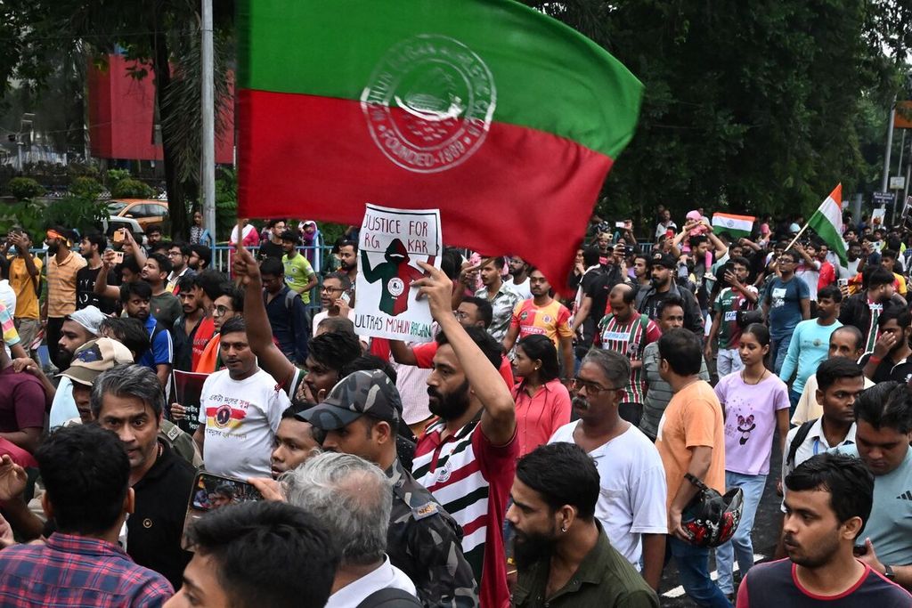 Pendukung sepak bola dari Bengal Timur dan Mohun Bagal bergabung dalam unjuk rasa, Minggu (18/8/2024), yang mengecam pemerkosaan dan pembunuhan terhadap seorang dokter di Kolkata, Negara Bagian Bengal Barat, India. 