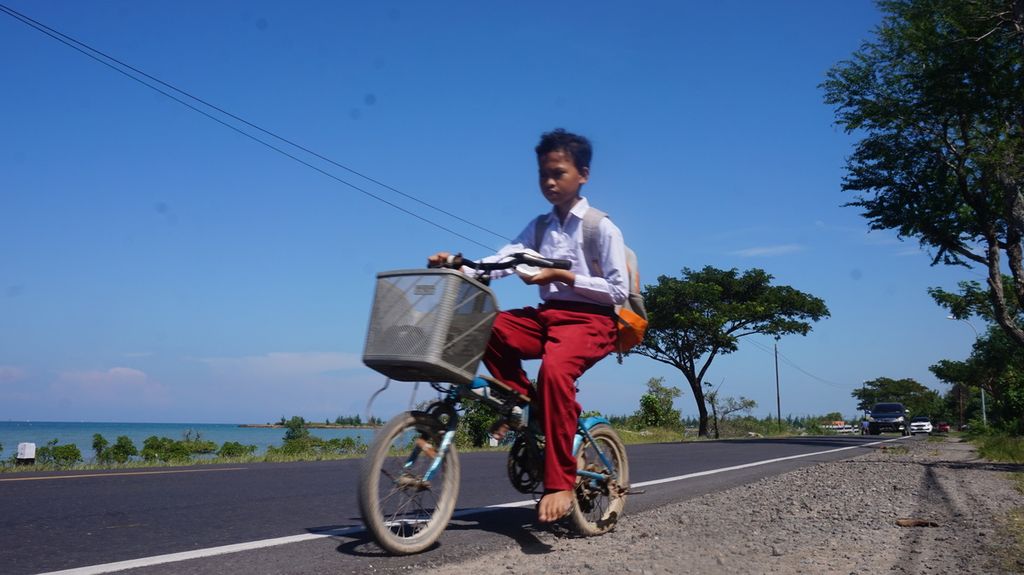 Anak-anak nelayan bersepeda sepulang sekolah di Jalan Raya Pamekasan-Sumenep, Pulau Madura, Jawa Timur, Senin (20/6/2022). Pemerataan pembangunan prasarana dan sarana transportasi serta utilitas, termasuk telekomunikasi, mendorong peningkatan kualitas sumber daya manusia pesisir. Anak-anak nelayan dapat menikmati pendidikan berkualitas setara dengan masyarakat perkotaan.