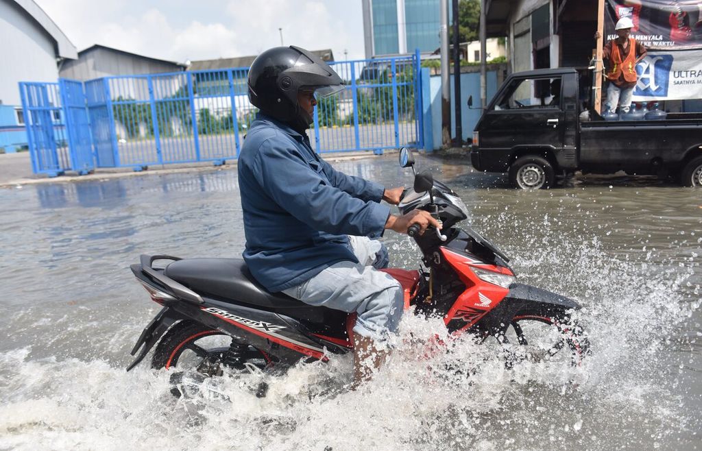 Pengendara menerobos banjir rob yang melanda jalan menuju Pelabuhan Ujung, Kota Surabaya, Jawa Timur, Senin (16/5/2022). 