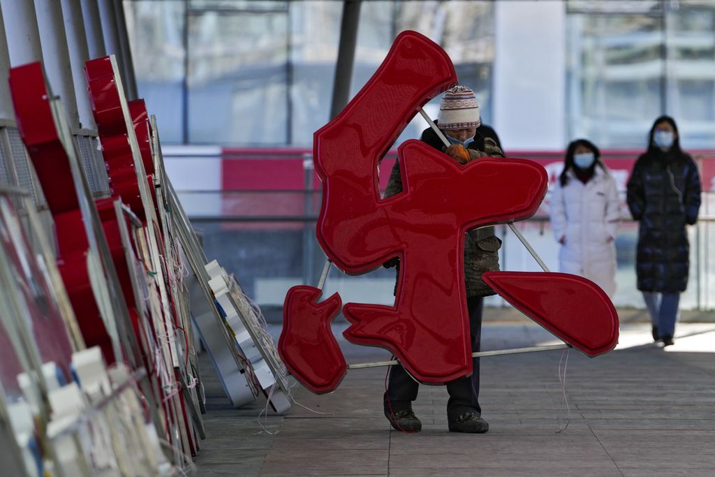Seorang pekerja membawa sebuah huruf yang melambangkan Kebahagiaan jelang perayaan Tahun Baru Imlek di Beijing, China, Selasa (25/1/2022). 