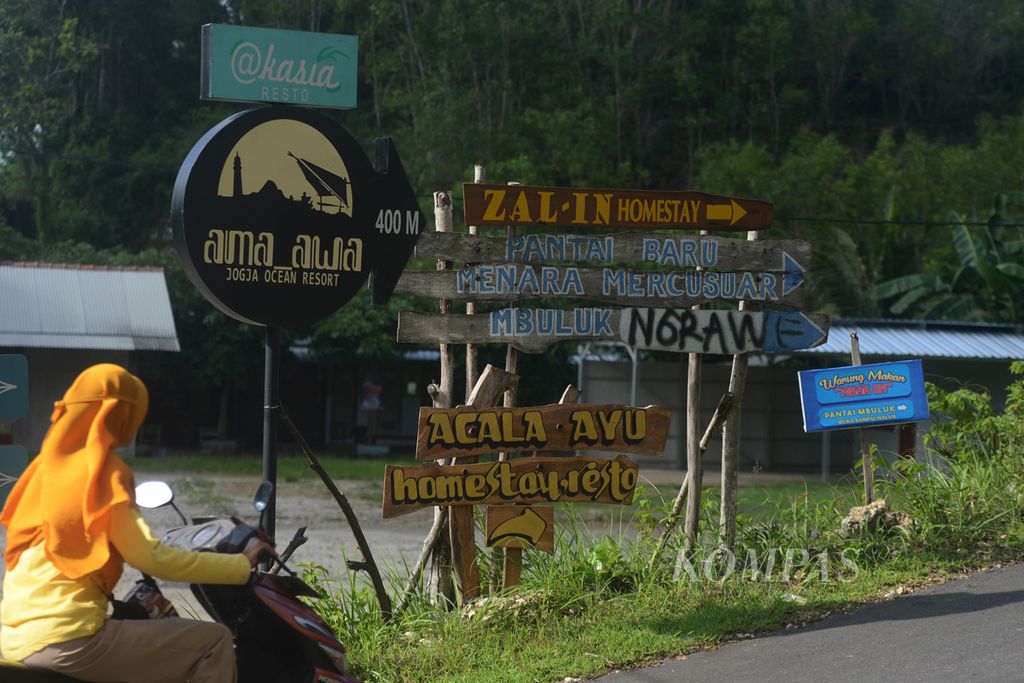 Warga melintas di depan papan penunjuk arah menuju sejumlah hotel dan penginapan di Kecamatan Tanjungsari, Gunungkidul, DI Yogyakarta, Jumat (26/1/2024).