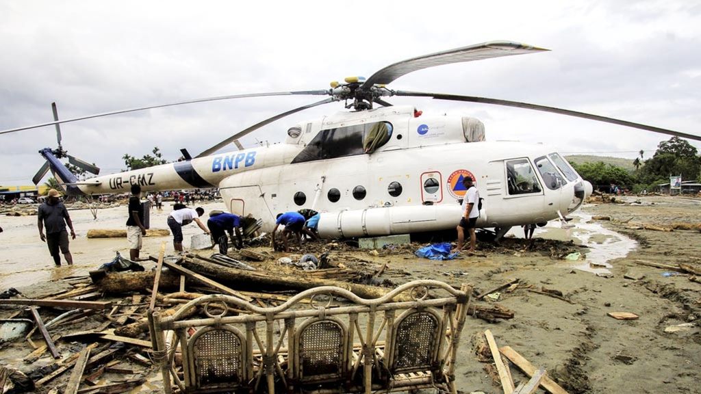 Warga berada di dekat helikopter yang bergeser dari tempatnya akibat banjir bandang di Sentani, Kabupaten Jayapura, Papua, pada Maret 2019.