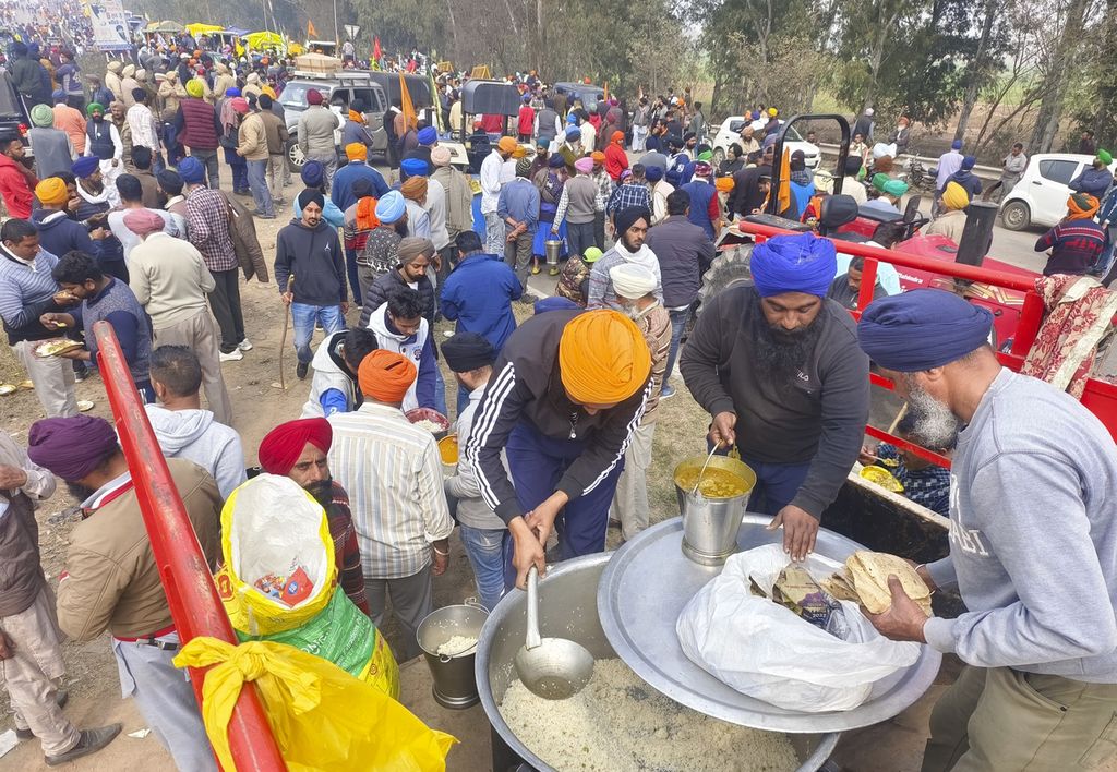 Petani India mengambil jatah makan di tengah unjuk rasa menuju New Delhi, Selasa (13/2/2024).