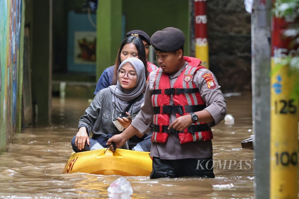 Wartawan menggunakan perahu saat meliput banjir di Kecamatan Jatinegara, Jakarta Timur, Jumat (15/3/2024). 