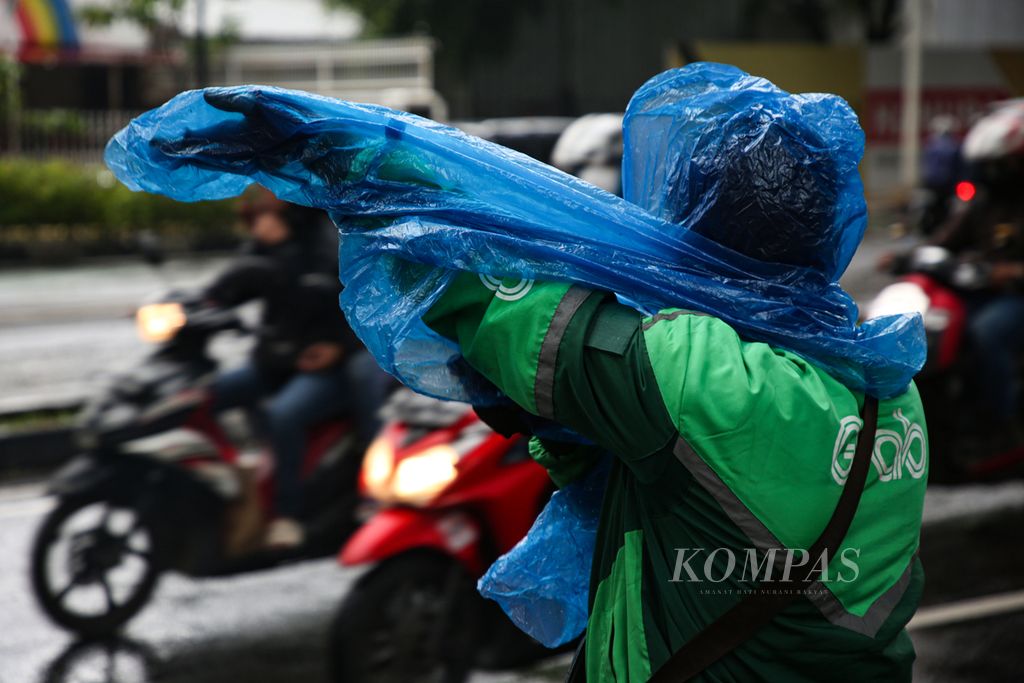 Pengemudi ojek daring mengenakan jas hujan saat hujan mengguyur di jalan layang Prof Dr Satrio, Jakarta Selatan, Rabu (15/3/2023).