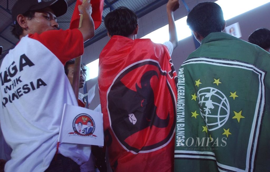Two supporters holding different party flags joined in to enliven the campaign of presidential duo Megawati Soekarnoputri - Hasyim Muzadi which was quiet at the Basketball Hall, Gelora Bung Karno Complex, Jakarta, on Friday (4/6/2004).