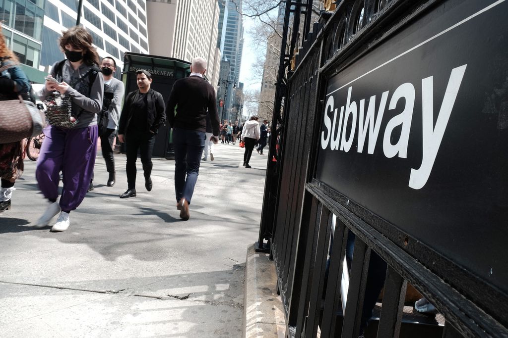 Orang-orang berjalan di dekat perhentian kereta bawah tanah di tengah kota Manhattan yang sibuk, Rabu (13/4/2022), setelah Departemen Kepolisian New York (NYPD) menangkap terduga pelaku penembakan di stasiun metro sehari sebelumnya yang melukai 23 orang. 