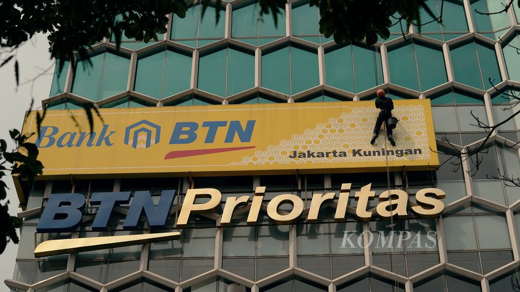 Pekerja membersihkan papan BTN di kawasan Setiabudi, Jakarta Selatan, Minggu (30/1/2022). 