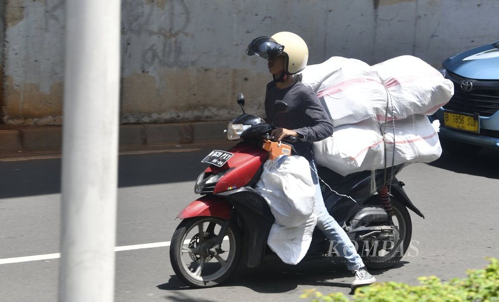 Kurir membawa barang menggunakan sepeda motor di kawasan Setiabudi, Jakarta Selatan, Selasa (9/11/2021). 