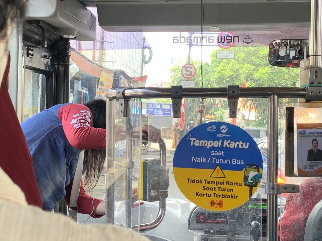 Seorang penumpang melakukan <i>tap in </i>di bus Transjakarta koridor 1M, rute Blok M-Meruya, Sabtu (19/11/2022). Sekitar tiga kali ia mencoba melakukan <i>tap in,</i> tetapi mesin tempel kartu tidak merespons. 
