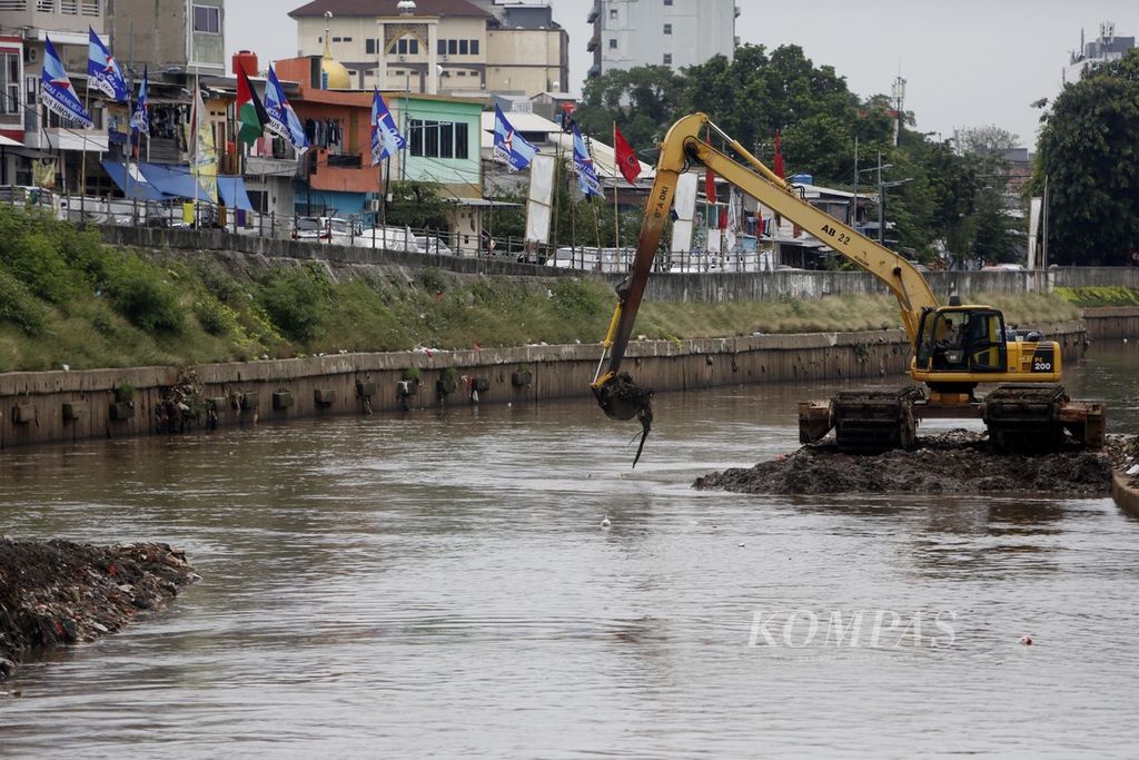 Alat berat dioperasikan untuk mengeruk lumpur di dasar Sungai Ciliwung yang memisahkan kawasan Jatinegara dengan Tebet, Jakarta, Kamis (4/1/2023).