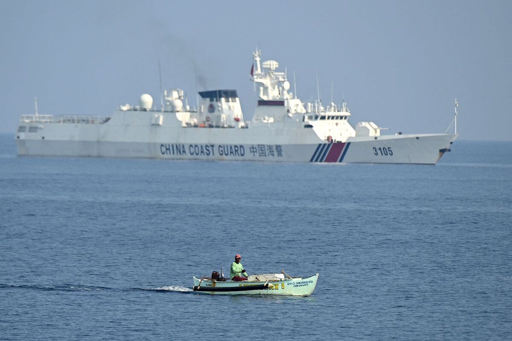 Seorang nelayan Filipina melintasi kapal Penjaga Pantai China di perairan Scarborough yang disengketakan di Laut China Selatan. China mengambil alih kendali atas Scarborough dari Filipina di tahun 2012 dan menempatkan berbagai kapal di sana untuk membatasi akses nelayan Filipina. 
