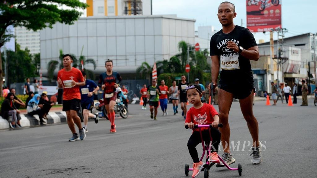 Salah satu pelari mengajak anaknya saat mengikuti ajang lari Semarang 10K di Kota Semarang, Jawa Tengah, Minggu (16/12/2018). 
