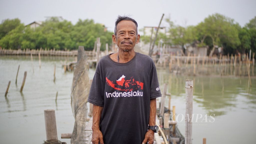Slamet (68), warga Desa Timbulsloko, Kecamatan Sayung, Demak, Jawa Tengah, yang terus bertahan di daerahnya yang hampir tenggelam akibat abrasi dan air rob.