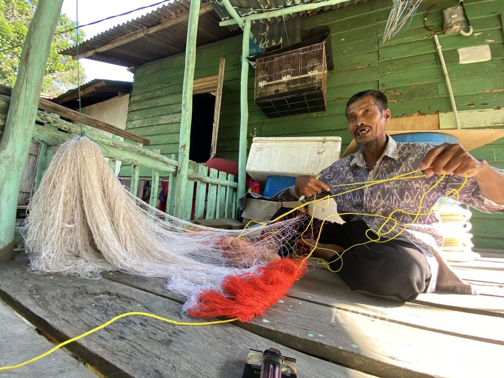 Ramli (52), nelayan tradisional di Kampung Pasir Panjang, Kecamatan Galang, Kotam, sedang merajut jaring di rumahnya, Rabu (27/9/2023). 