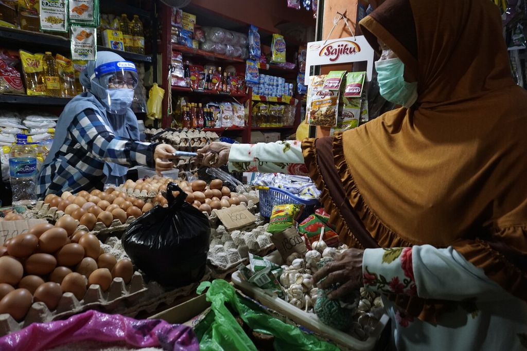 Ketua Pedagang Pasar Rapak, Fatmawati (48), menerima uang dari pembeli dengan mengenakan pelindung wajah dan masker di Pasar Rapak, Kelurahan Muara Rapak, Kecamatan Balikpapan Utara, Kota Balikpapan, Kalimantan Timur, 26 Juli 2020.